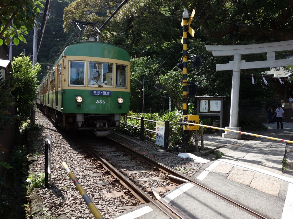 御霊神社の鳥居の前の踏切に近づく江ノ電